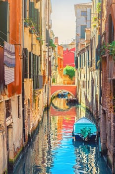 Venice cityscape with narrow water canal with boats moored between brick walls of old buildings and stone bridge, Veneto Region, Northern Italy. Typical Venetian view, vertical view