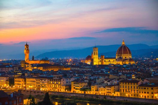 Top aerial panoramic evening view of Florence city with Duomo Cattedrale di Santa Maria del Fiore cathedral and Palazzo Vecchio palace at night dusk twilight, city lights, blue sky, Tuscany, Italy