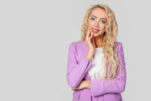 The concept of beauty, emotions and women. Attractive European blonde woman, feeling happy, touching her cheek with her palm, tilting her head, looking beautifully at the camera, looking flirty