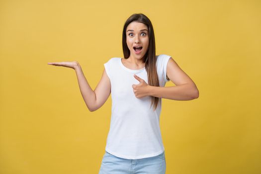 Portrait of magnificent pretty lovely gorgeous adorable stylish cheerful girl in casual white t-shirt, pointing aside with hand and finger, isolated over yellow background.