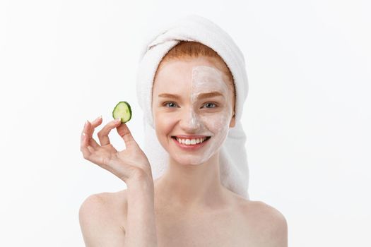 Attractive Young Woman with beautiful clean skin. White mask and cucumbers. Beauty treatments and cosmetology spa therapy. White background.