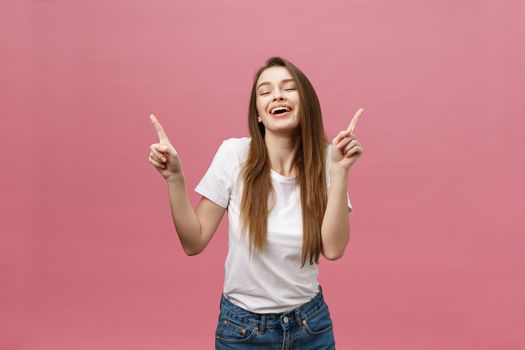 Photo of happy young woman standing and poiting finger isolated over pink background