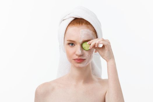 Attractive Young Woman with beautiful clean skin. White mask and cucumbers. Beauty treatments and cosmetology spa therapy. White background.