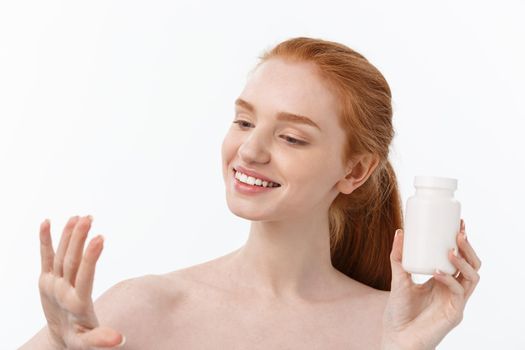 Portrait of good-looking young caucasian woman holding pills, trying to take care of immune system and health over gray background