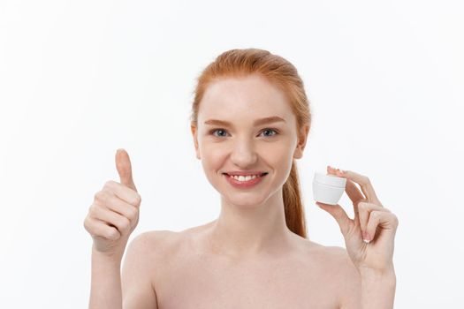 portrait of beautiful woman smiling while taking some facial cream isolated on white background with copy space