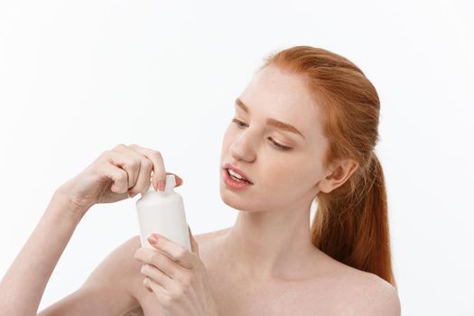 Portrait of good-looking young caucasian woman holding pills, trying to take care of immune system and health over gray background