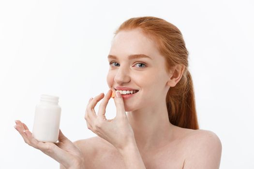 Portrait of good-looking young caucasian woman holding pills, trying to take care of immune system and health over gray background