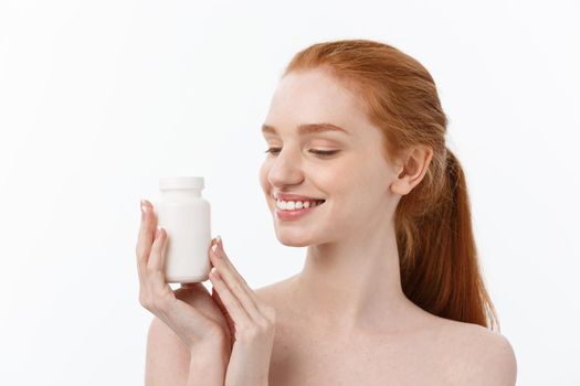 Portrait of good-looking young caucasian woman holding pills, trying to take care of immune system and health over gray background