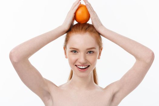 Great food for a healthy lifestyle. Beautiful young shirtless woman holding piece of orange standing against white background