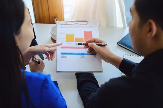 Teamwork concept, consultation, male economist holding pen pointing to budget, finance and investment documents, discussing and planning finances with female advisors in conference room