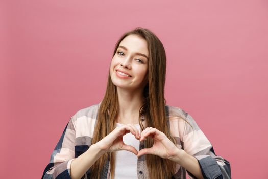 Lifestyle Concept: Beautiful attractive woman in white shirt making a heart symbol with her hands.