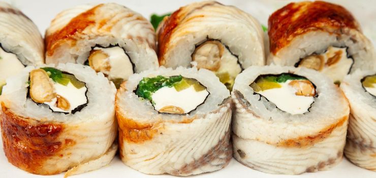 Sushi roll with eel and chuka salad on a white plate, classic Japanese sushi. Traditional Japanese food with maki. Delicious pieces of sushi. For the restaurant menu. copyspace.