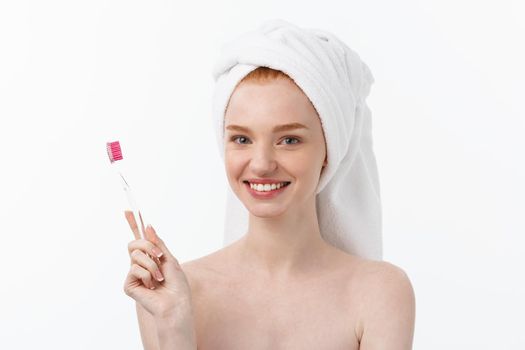 Portrait of young woman with toothbrush on grey background