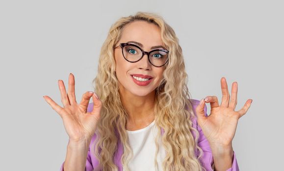 Portrait of a satisfied positive and charismatic happy woman in glasses, showing ok signs and smiling in approval, I recommend. Lady making double taps. Okay.