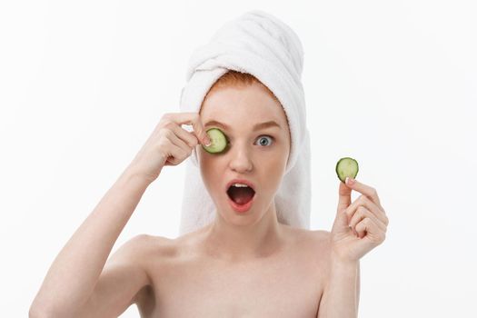 Attractive Young Woman with beautiful clean skin. White mask and cucumbers. Beauty treatments and cosmetology spa therapy. White background.