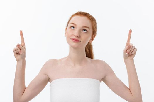 Portrait of young redhead female with perfect freckled skin showing something interesting at copy space wall for your advertising content