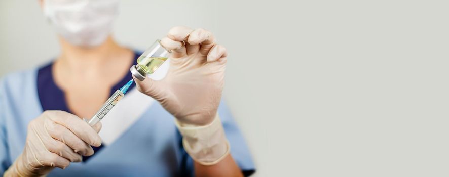 Hand of a doctor or nurse in nitrile gloves with a syringe needle vaccinated against influenza, measles, coronavirus COVID-19 for vaccinating children and adults, the concept of medicine and medicines