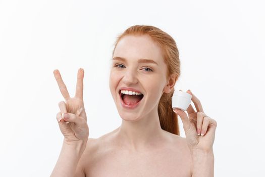 portrait of beautiful woman smiling while taking some facial cream isolated on white background with copy space