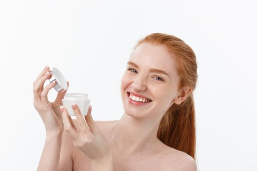 portrait of beautiful woman smiling while taking some facial cream isolated on white background with copy space