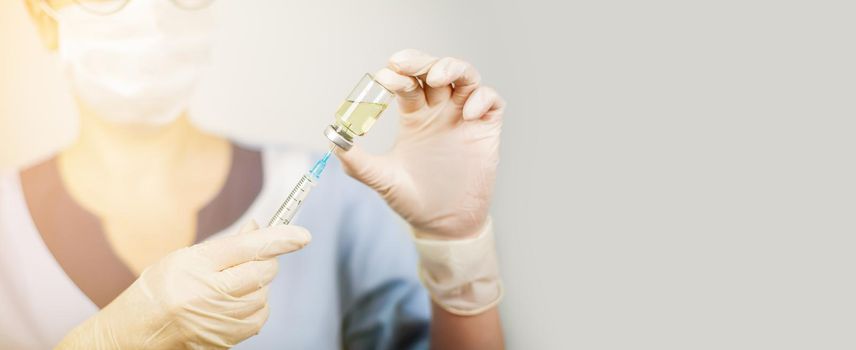 Hand of a doctor or nurse in nitrile gloves with a syringe needle vaccinated against influenza, measles, coronavirus COVID-19 for vaccinating children and adults, the concept of medicine and medicines