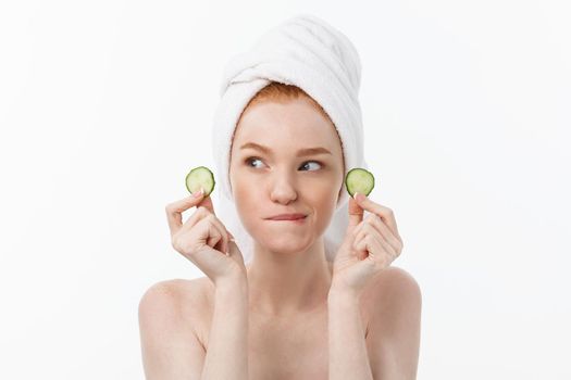 Attractive Young Woman with beautiful clean skin. White mask and cucumbers. Beauty treatments and cosmetology spa therapy. White background.