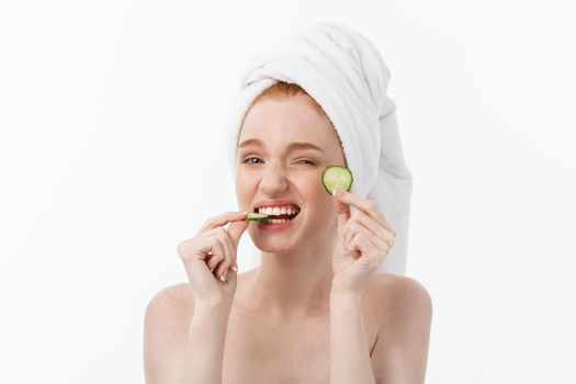 Attractive Young Woman with beautiful clean skin. White mask and cucumbers. Beauty treatments and cosmetology spa therapy. White background.