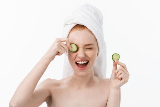 Attractive Young Woman with beautiful clean skin. White mask and cucumbers. Beauty treatments and cosmetology spa therapy. White background.