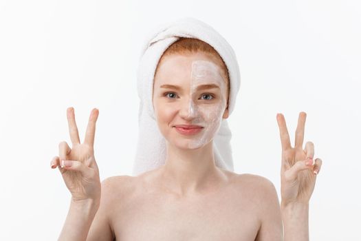 Beautiful caucasian woman applying mask on her face with two fingers sign white background