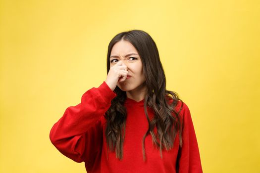 Smell bad. Young lady makes disgusts the smell isolate on yellow background