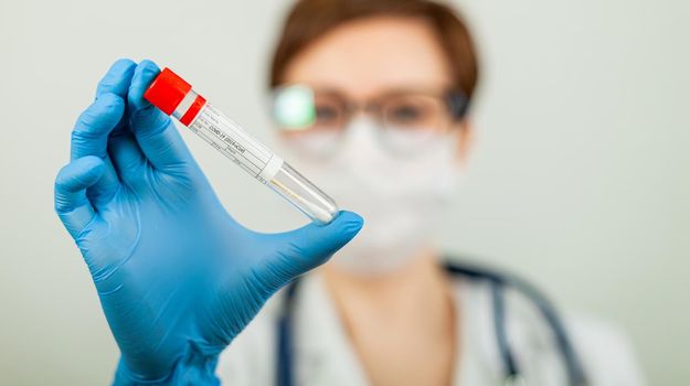 Test for coronavirus Covid-19. Female doctor or nurse doing lab analysis of a nasal swab in a hospital laboratory. Medical technologist holding a COVID-19 smear kit, wearing protective gloves from