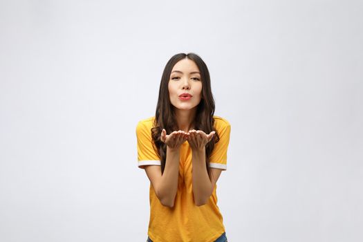 Portrait of a young cute woman blowing kiss at camera isolated on white background.