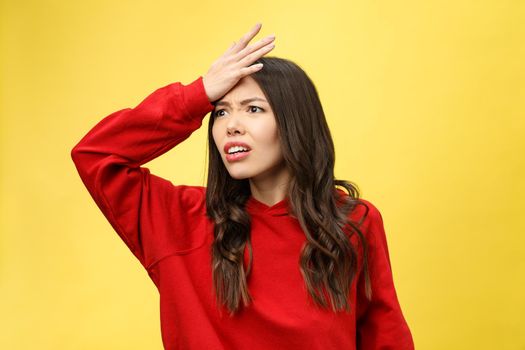 Shocked scared beautiful young woman with mouth widely opened, stares at camera realizes that she disappoint with something, isolated over yellow studio background
