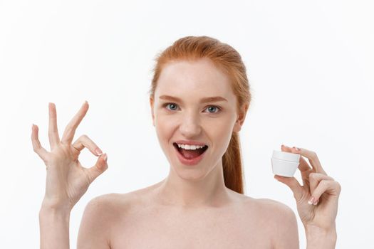 portrait of beautiful woman smiling while taking some facial cream isolated on white background with copy space