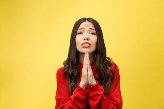 Getting concentration from space. Portrait of good-looking young european female, holding hands in pray, focused on praying or wishing over yellow background.