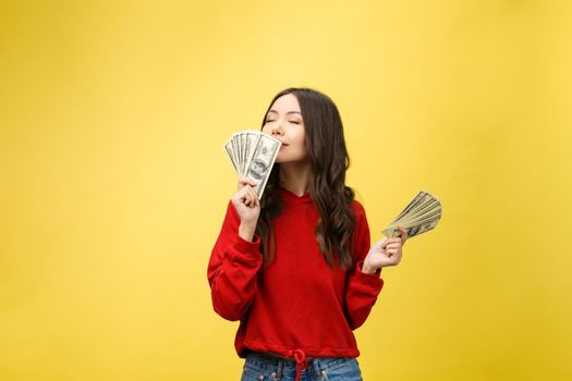 Closeup of young beautiful woman with us dollar money in hand over yellow background, with copy space.