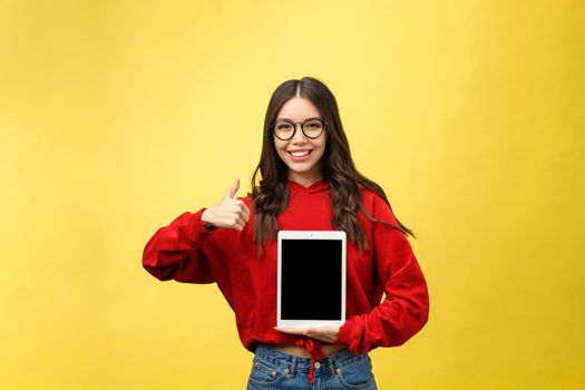 Woman using digital tablet computer PC isolated on yellow background.