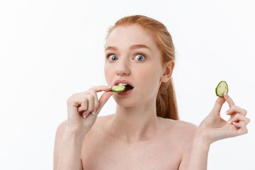 Attractive Young Woman with beautiful clean skin. White mask and cucumbers. Beauty treatments and cosmetology spa therapy. White background.