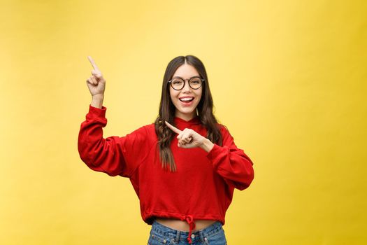 Young beautiful asian woman pointing to copyspace, isolated on yellow background.