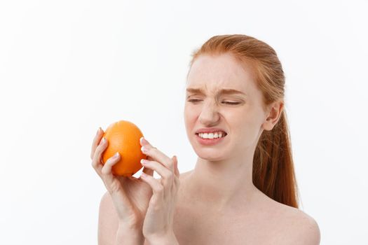 Serious Cuacasian woman with orange on hand isolate over background. spa.