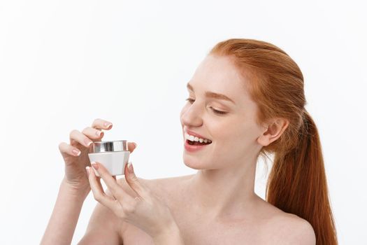 portrait of beautiful woman smiling while taking some facial cream isolated on white background with copy space