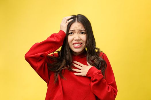 Shocked scared beautiful young woman with mouth widely opened, stares at camera realizes that she disappoint with something, isolated over yellow studio background