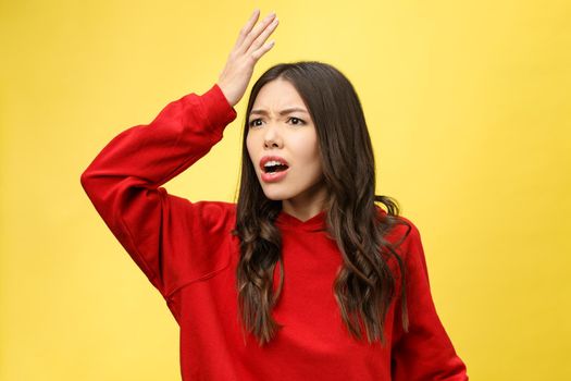 Shocked scared beautiful young woman with mouth widely opened, stares at camera realizes that she disappoint with something, isolated over yellow studio background