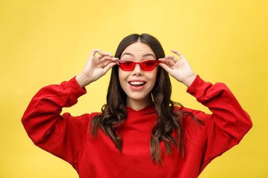 Pretty happy woman in red sunglasses over colorful background.