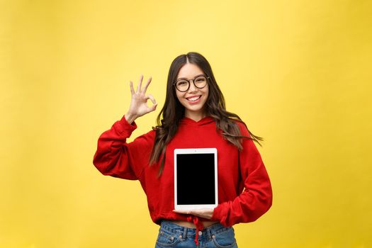 Woman using digital tablet computer PC isolated on yellow background.