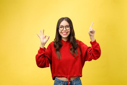 Young beautiful asian woman pointing to copyspace, isolated on yellow background.