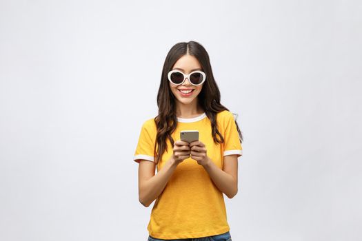 Content calm trendy nice cute adorable lovely attractive brunette caucasian girl with wavy hair in casual shirt, playing game in phone, isolated over grey background