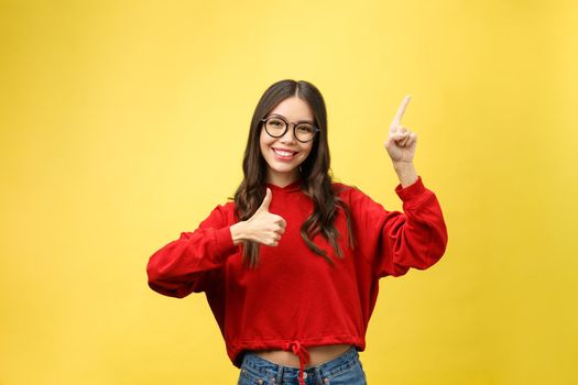 Young beautiful asian woman pointing to copyspace, isolated on yellow background.