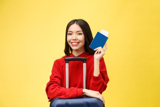 Woman travel. Young beautiful asian woman traveler with passport and suitcase on yellow background.