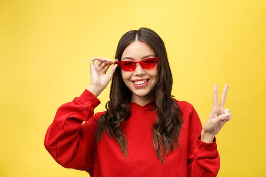 Pretty happy woman in red sunglasses over colorful background.