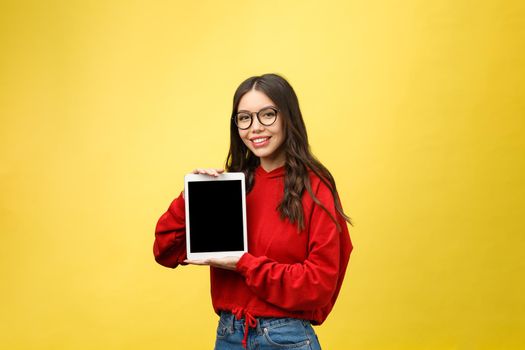 Woman using digital tablet computer PC isolated on yellow background.